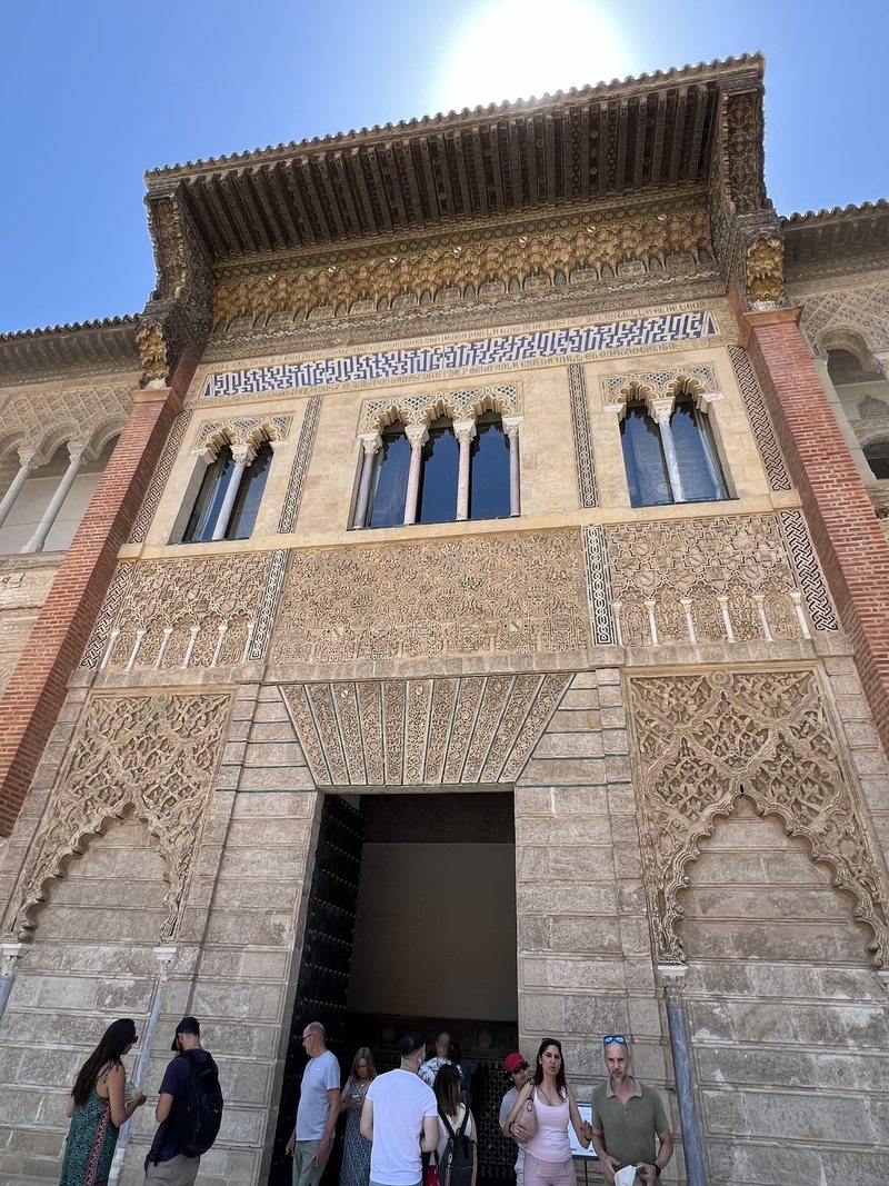 Visitors at a doorway beneath a tall carved façade in the Real Alcázar.
